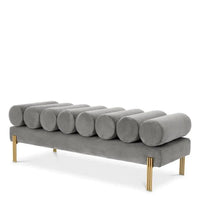 Bench Oxley, shown in greige gray with velvet, metal, and fixed cylindrical bolster backrest.