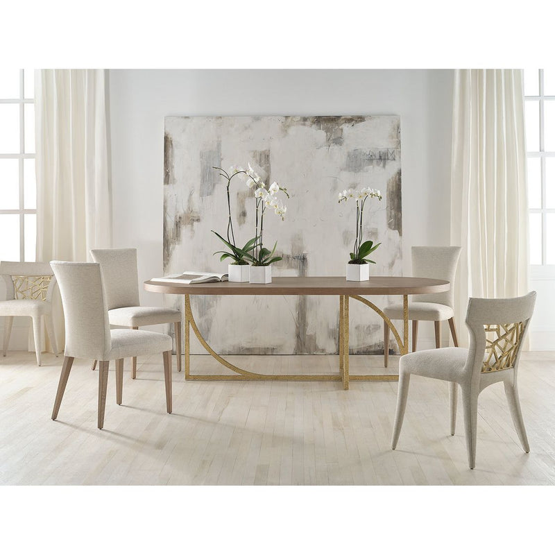 Alternate view of Conform Table, featuring textured metallic finish, wood, metal, and a oval dining surface.