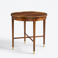 A round wooden end table with a warm medium-brown wood finish, featuring brass trim around the tabletop and brass caps on the legs, set against a plain light gray background.